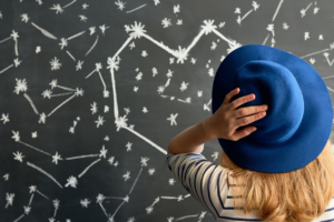 woman looking at a chalkboard marked with constellations
